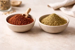 Manjistha powder and henna powder in labeled bowls under soft light