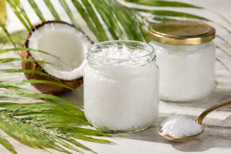 Glass jars of white coconut oil with tropical leaf backdrop for wholesale sourcing