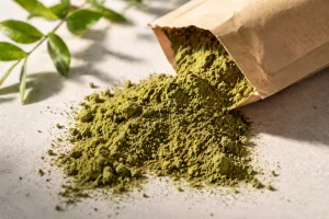 Green henna powder poured from a bag for bulk quality evaluation